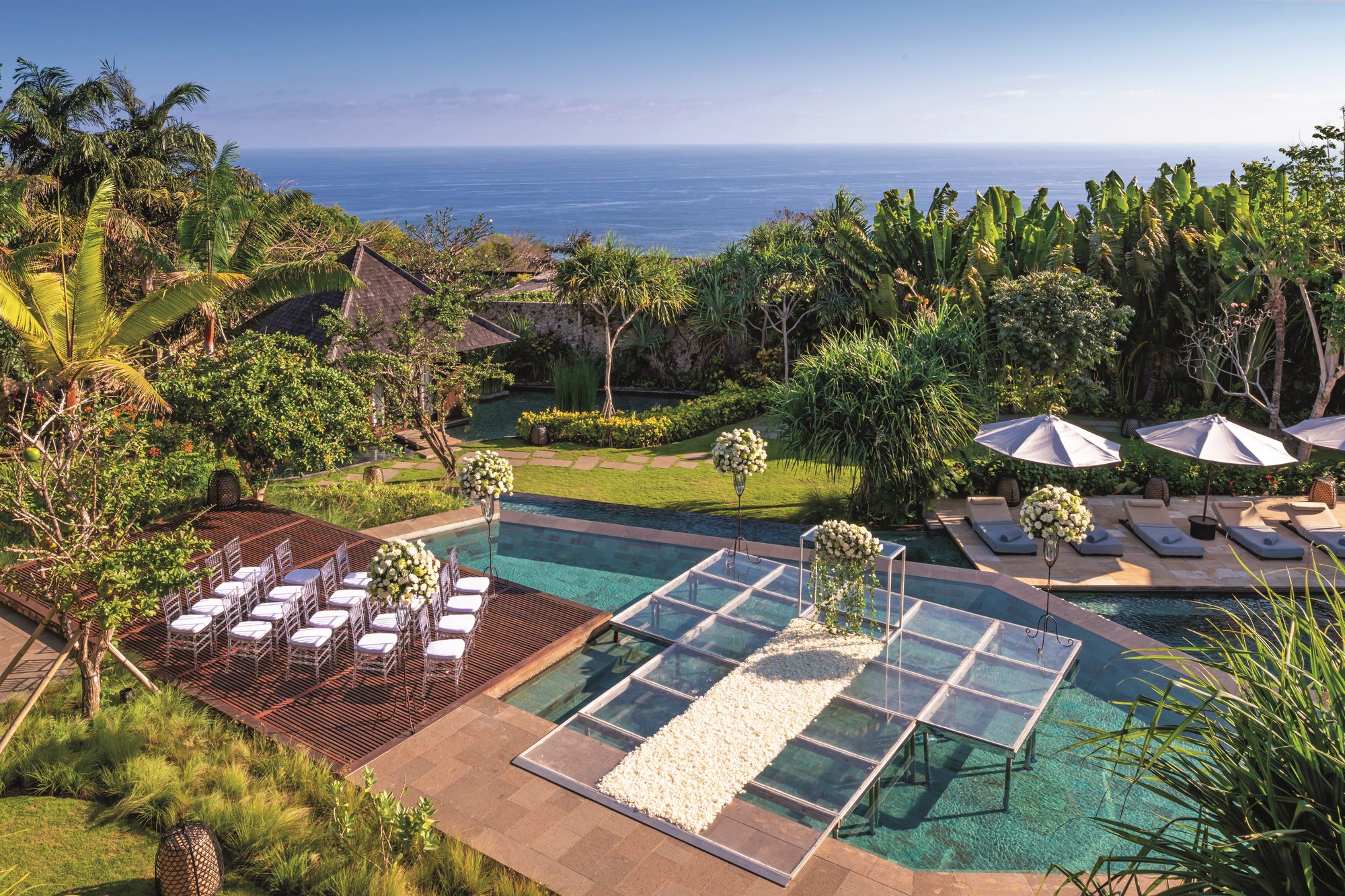Bulgari Resort Bali — a ceremony set on a glass walkway over the pool, the ocean beyond · Uluwatu, Indonesia
