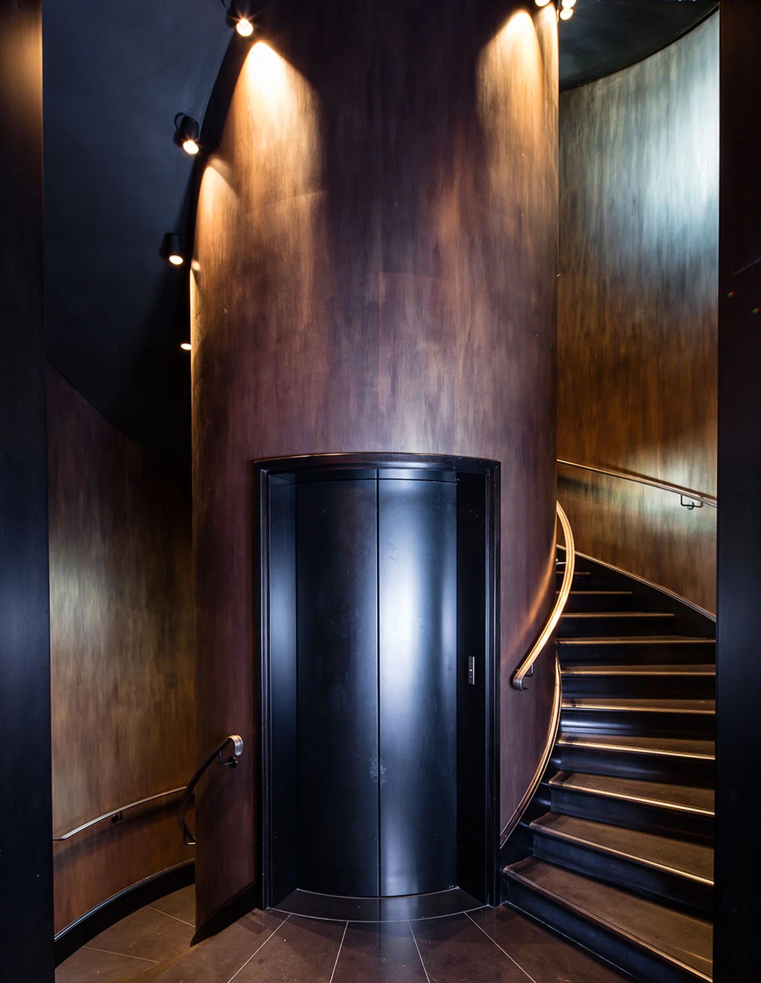 Villa Clara — the lift and spiral staircase in a bronze-lined hall · Rome, Italy