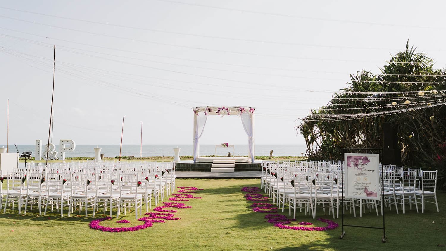 Villa Phalosa — a ceremony aisle lined with pink petals on the lawn · Seminyak, Indonesia