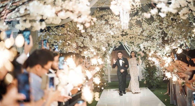 Villa Phalosa — a couple walking through a blossom-covered aisle · Seminyak, Indonesia