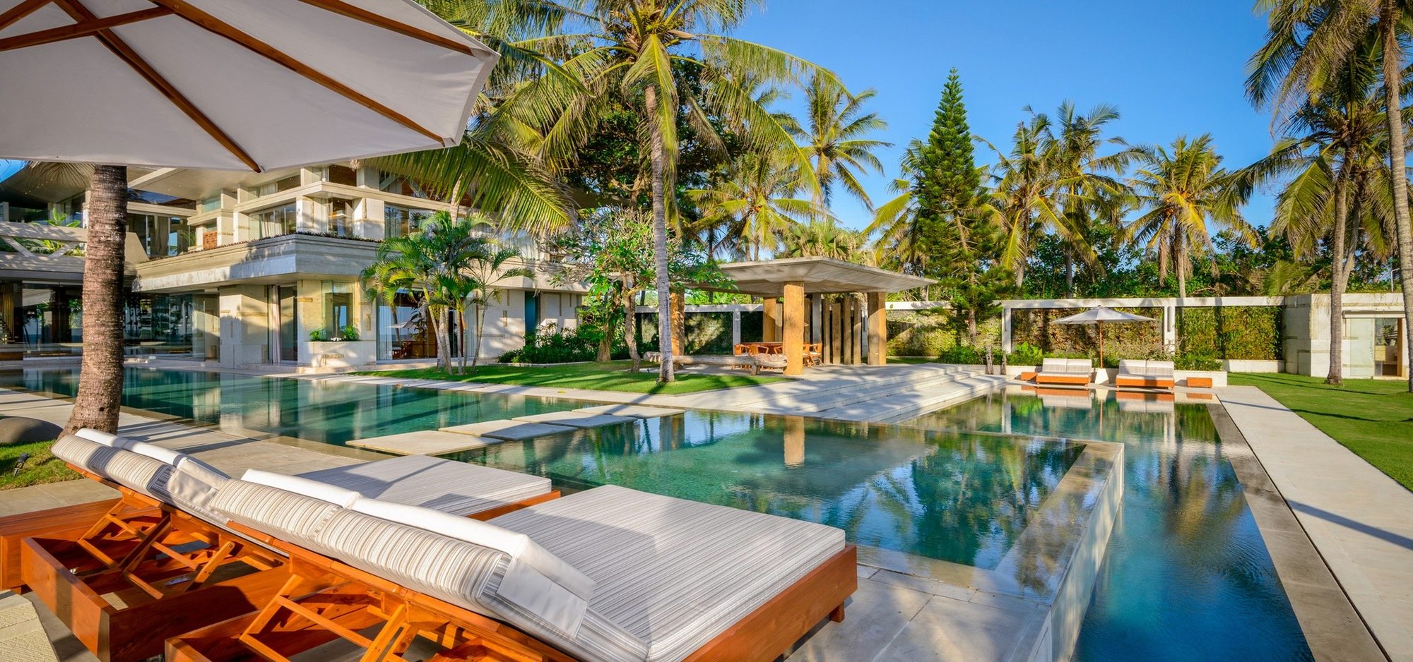 Villa Vedas — loungers beside the pool among palms · Bali, Indonesia